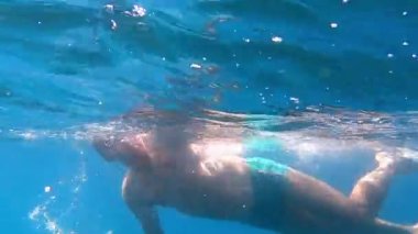 Gözlüklü adam mavi denizde kurbağalama yüzer. Yüksek kaliteli FullHD görüntüler