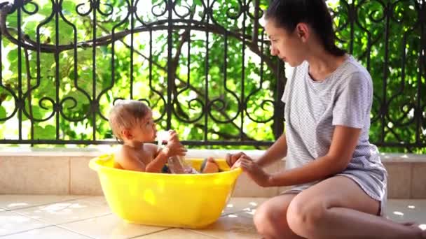 Mom Smiling Kisses Little Girl Sitting Bowl Water Balcony High — Stock Video