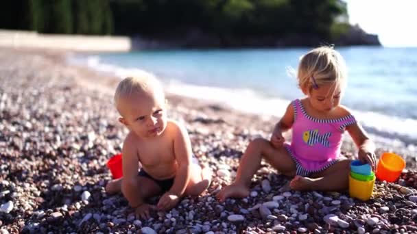 Menino Menina Estão Sentados Uma Praia Seixos Brincando Com Baldes — Vídeo de Stock