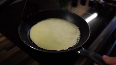 Man flips a pancake with a spatula in a frying pan. High quality 4k footage