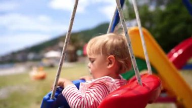 Little girl swinging on a rope swing with her eyes closed. High quality 4k footage