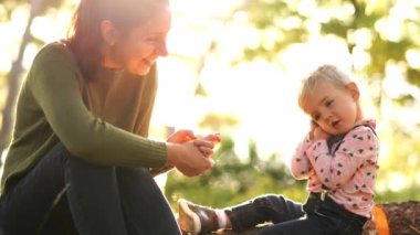 Mom hugs a little girl sitting on a sunny lawn. High quality 4k footage