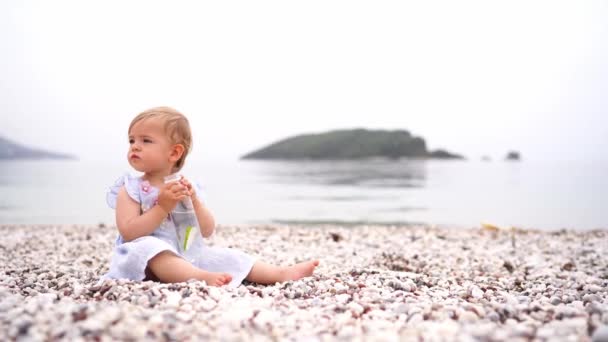 Menina Sentada Uma Praia Seixos Com Uma Garrafa Água Suas — Vídeo de Stock