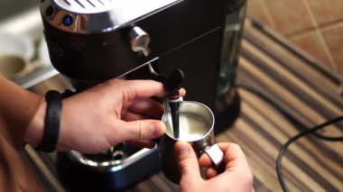 Man frothing milk with a frother on a carob coffee machine. High quality 4k footage