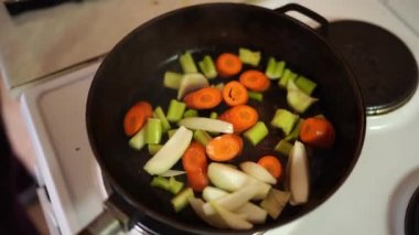 Woman pouring chopped vegetables into oil in a frying pan. High quality 4k footage