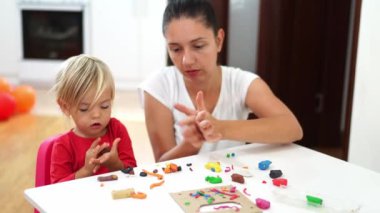 Mom with a little girl sculpt plasticine crafts at the table in the room. High quality 4k footage