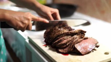 Housewife cuts roast beef into pieces on the table with a knife. High quality 4k footage