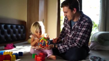 Dad plays with a little girl with multi-colored jigsaw puzzles. High quality 4k footage