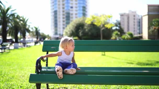 Маленькая Девочка Сидящая Скамейке Парке Повернув Голову Сторону Высококачественные Кадры — стоковое видео