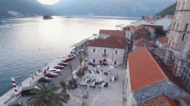 Wedding celebration in the courtyard of the church on the coast of Perast. Drone. High quality 4k footage