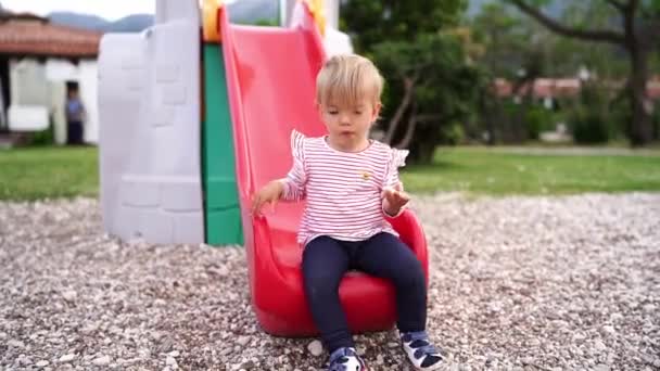 Little Girl Sits Slide Eats Piece Apple High Quality Fullhd — Stockvideo