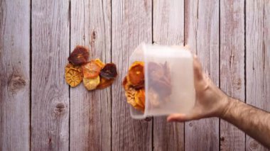 Photographer-stoker pours pieces of dried fruit on a wooden background for product photography. High quality 4k footage