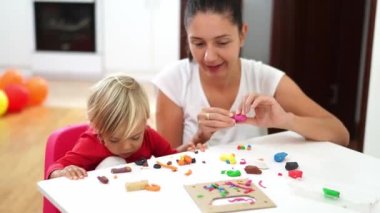 Smiling mother with little girl sculpt plasticine at the table. High quality 4k footage