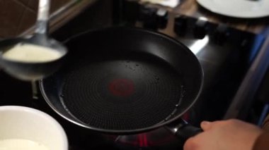Cook pours the dough for thin pancakes into the pan and puts it on the stove. High quality 4k footage