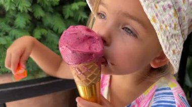 Little girl with a plastic spoon eats popsicles in a cone. High quality 4k footage
