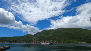 Small ferry floats on the sea against the backdrop of green mountains. High quality 4k footage