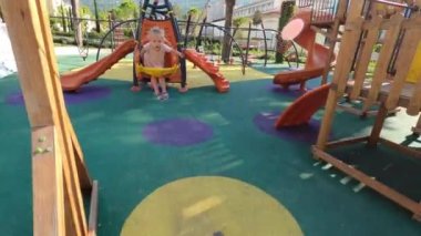 Little girl swings on a chain swing on a playground. High quality 4k footage