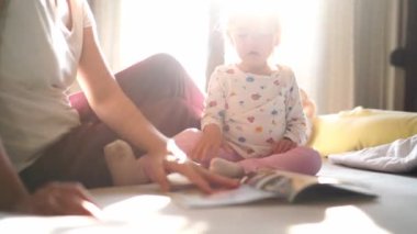 Mom reads a book to a little girl, running her finger along the lines. High quality 4k footage