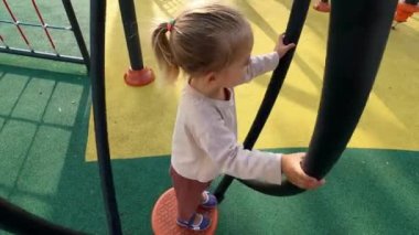 Little girl is spinning on a single standing carousel while holding on to the handrails. High quality 4k footage