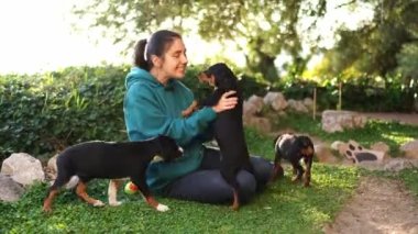 Smiling girl sitting on green grass and playing with little puppies. High quality 4k footage