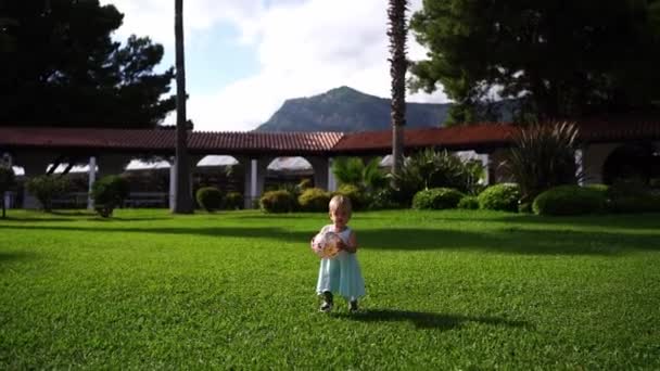 Little Girl Ball Her Hands Walks Green Lawn Falls High — Stockvideo