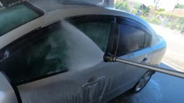 Car is washed in the garage at the car wash with a hose with soapy water. High quality 4k footage