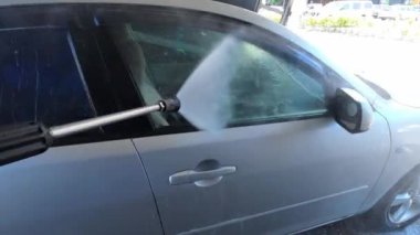 Side of the car is washed with water from a hose at a car wash. High quality 4k footage