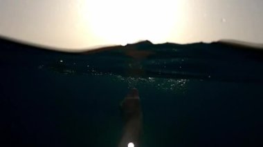Male legs dangle underwater, raising splashes and bubbles. High quality FullHD footage