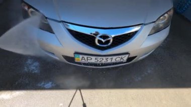 Hood, arabanın farları ve tekerlekleri oto yıkamada hortumla yıkanır.