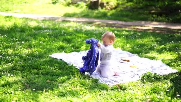 Small Baby Sits Blanket Green Grass Shakes Out Sweater High — Video Stock