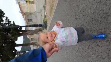 Little laughing girl runs along the road holding her father hand. High quality 4k footage