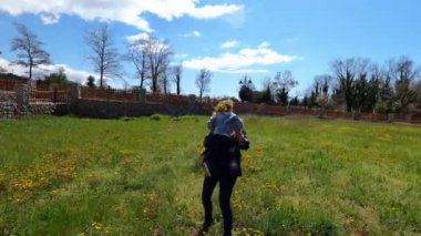 Mom takes a little girl in her arms and spins with her in a clearing with dandelions. High quality 4k footage