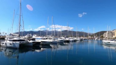 Row of sailing yachts are moored near the shore against the backdrop of mountains. High quality 4k footage