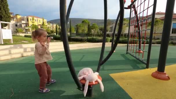 Little Girl Spins Plush Rabbit Vertical Single Carousel Hits Her — Stockvideo