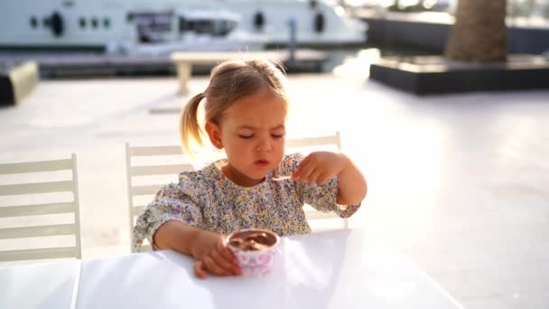 Little Girl Eats Chocolate Ice Cream Spoon Cup Sitting Table — Stok video