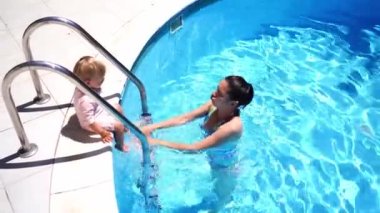 Mom picks up a little girl, while standing in the pool. High quality 4k footage