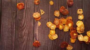 Pieces of dried fruits are artistically scattered on a wooden table. High quality 4k footage