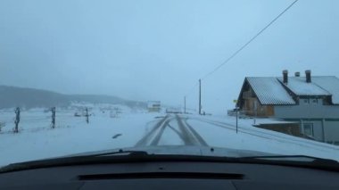 Car drives along a snowy road in the village of Zabljak. Montenegro. High quality 4k footage