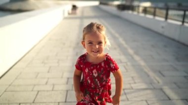 Little laughing girl runs along the sunny cobbled promenade of the sea. High quality FullHD footage