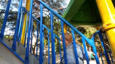 Little girl climbs the stairs to the slide holding on to the handrail. High quality 4k footage