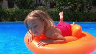 Dad rides a little girl on an inflatable ring in the pool. High quality 4k footage