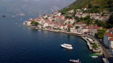 Perast kıyısında yeşil dağların eteğinde beyaz tekne duruyor. Karadağ. Yüksek kalite 4k görüntü