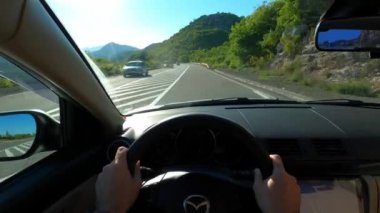 View from the driver seat of the car on the road among the green mountains. High quality 4k footage