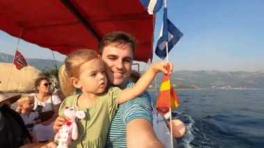 Dad with a little girl in his arms are sailing on a sightseeing boat on the sea. High quality 4k footage