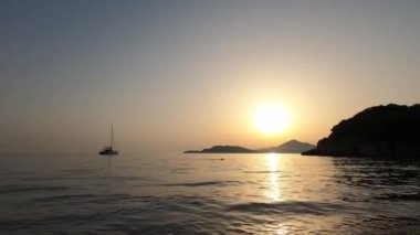 Sailboat floats on the sea against the backdrop of the setting sun. High quality 4k footage