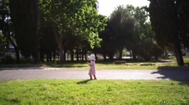 Little girl running on the grass in the park, waving her arms. High quality FullHD footage