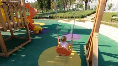 Dad swings a little girl on a chain swing at the playground. High quality 4k footage
