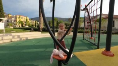 Little girl spins a plush rabbit on a vertical single carousel. High quality 4k footage
