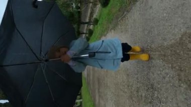 Little girl with an umbrella runs along a wet asphalt path in the rain. High quality 4k footage