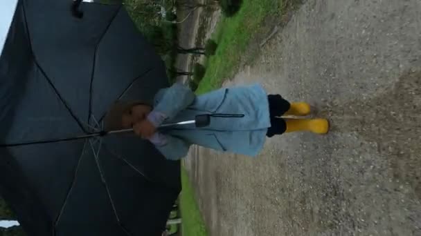 Kleines Mädchen Mit Regenschirm Läuft Regen Über Einen Nassen Asphaltweg — Stockvideo